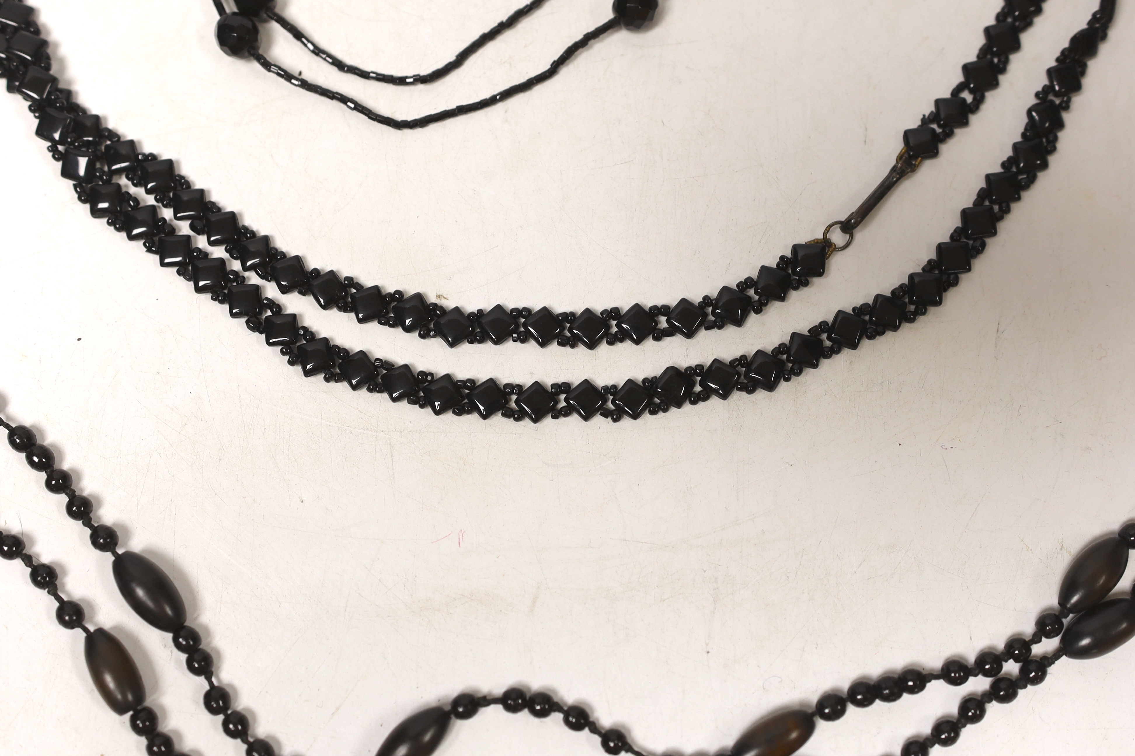 Three assorted necklaces including Whitby jet, largest 162cm.